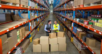 Men discussing over boxes in warehouse