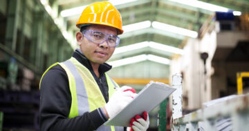 Man with hardhat and clipboard in warehouse