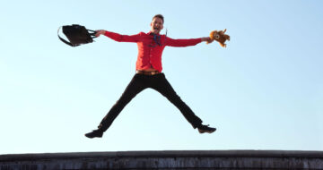 Man jumping in the air with bag and teddy