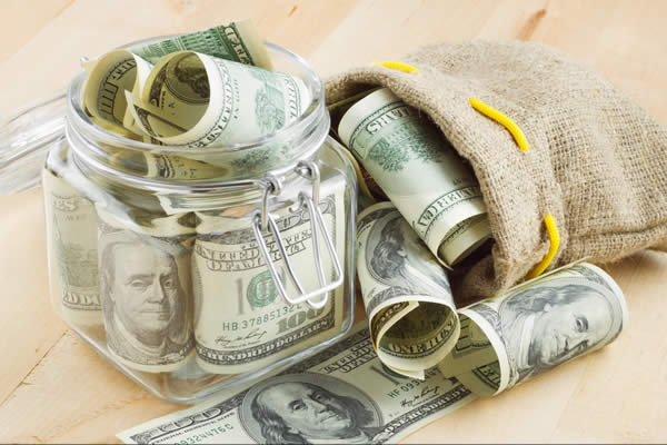 Money in jar and bag on a table