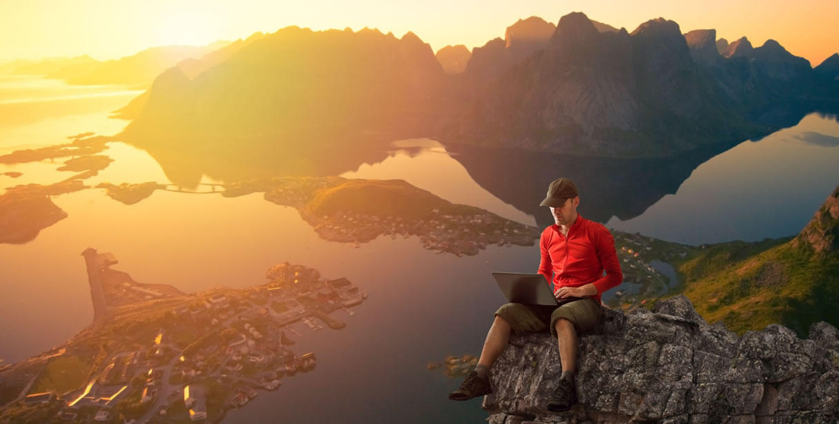 Man working on computer on mountain