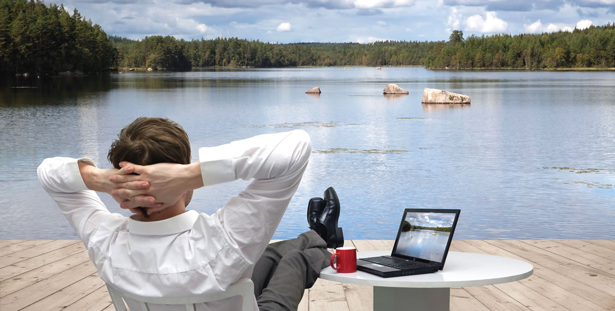 Man with PC relaxing by lake