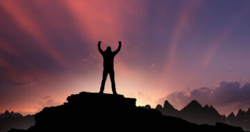 Man at top of mountain at sunset