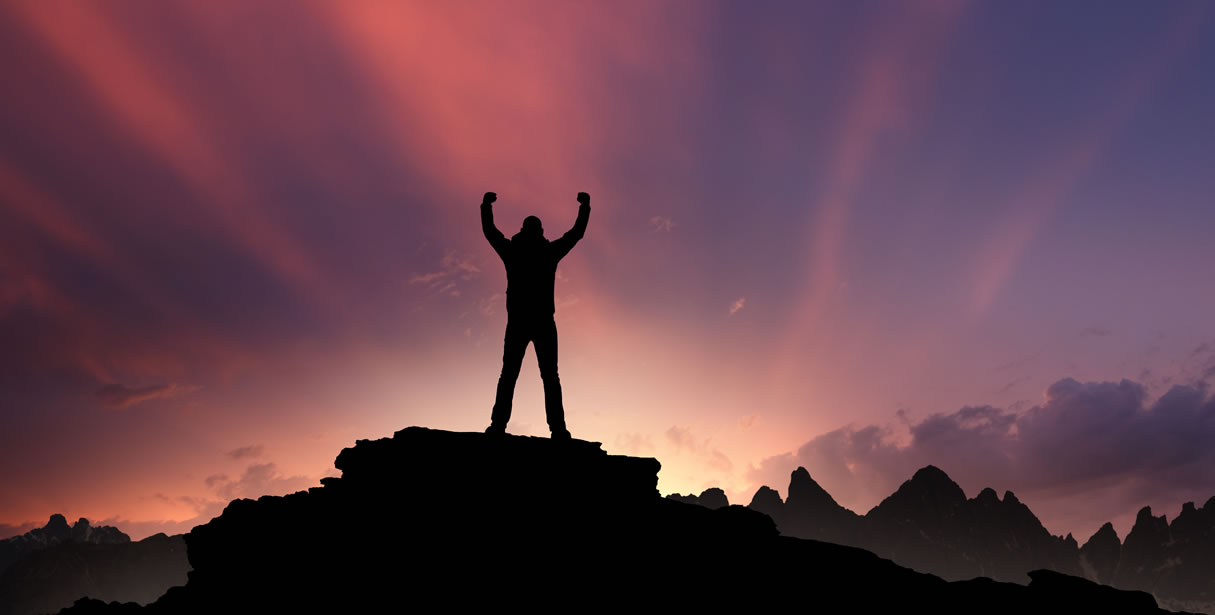 Man at top of mountain at sunset