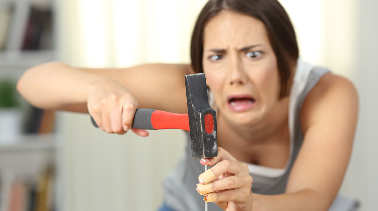 Woman hitting finger with hammer