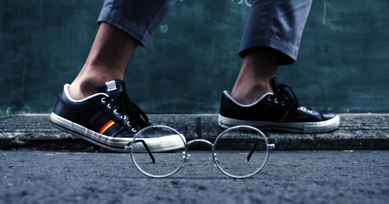 Man in sneakers with glasses in front